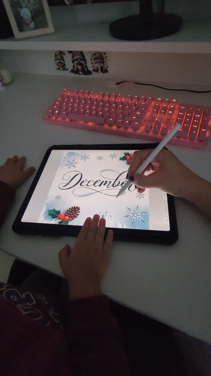 Hands drawing December-themed artwork on a tablet with stylus