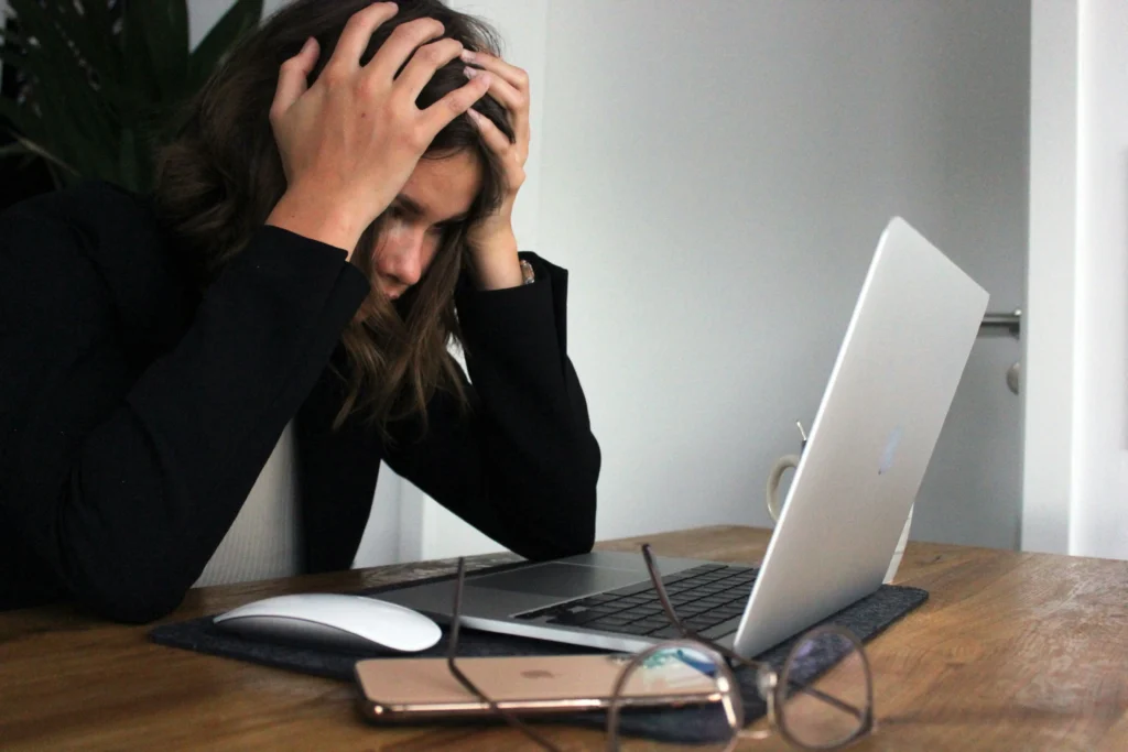 Why It’s Okay to Start Small (And Stay Consistent) 1 Woman stressed at desk with laptop — reminder to start small and stay consistent